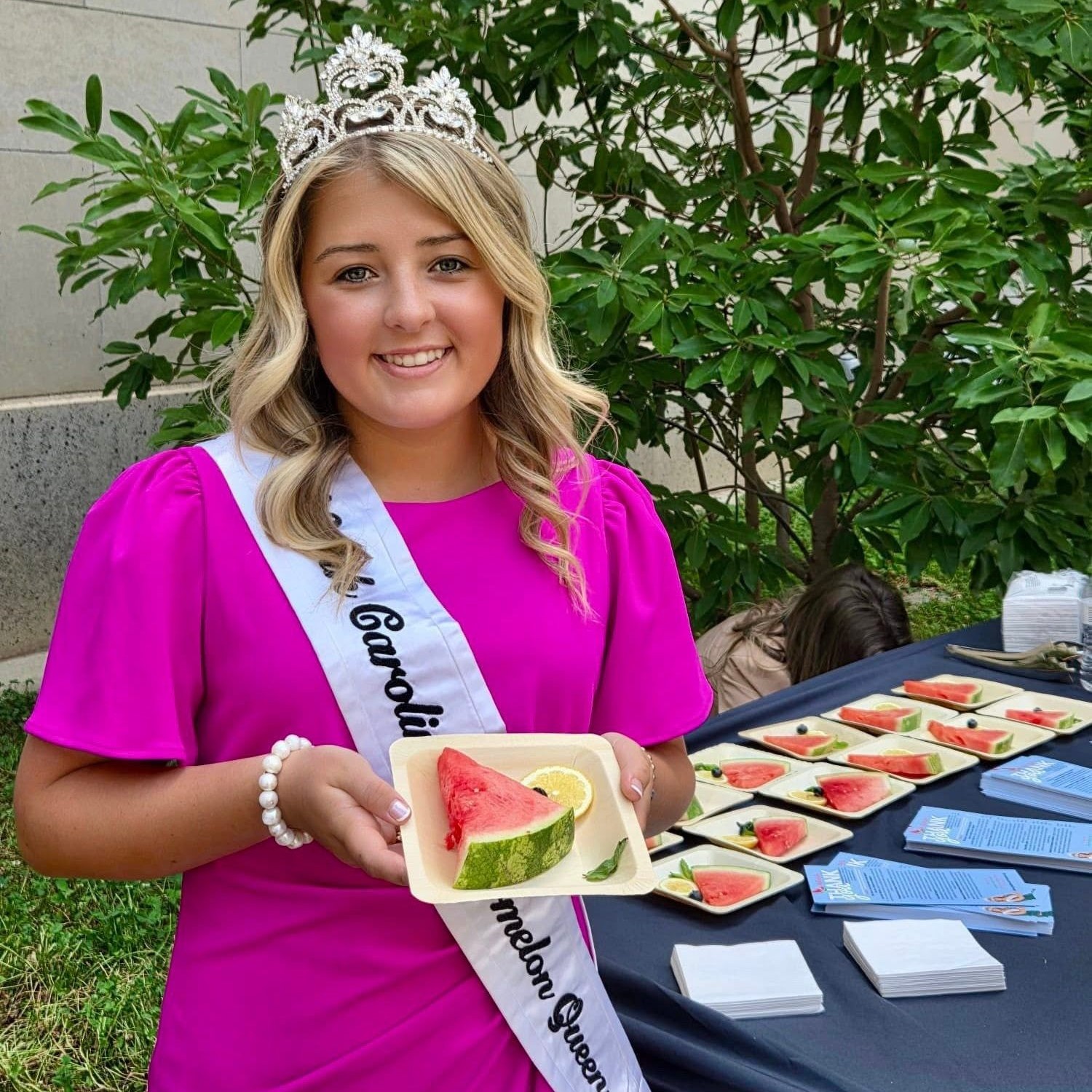 Lilah Byrum in crown and sash with a tray of cut watermelon